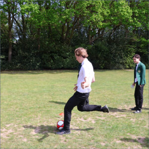 Two pupils in school uniforms playing football