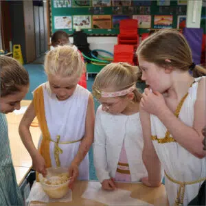 Year 3 pupils in Roman outfits baking cookies