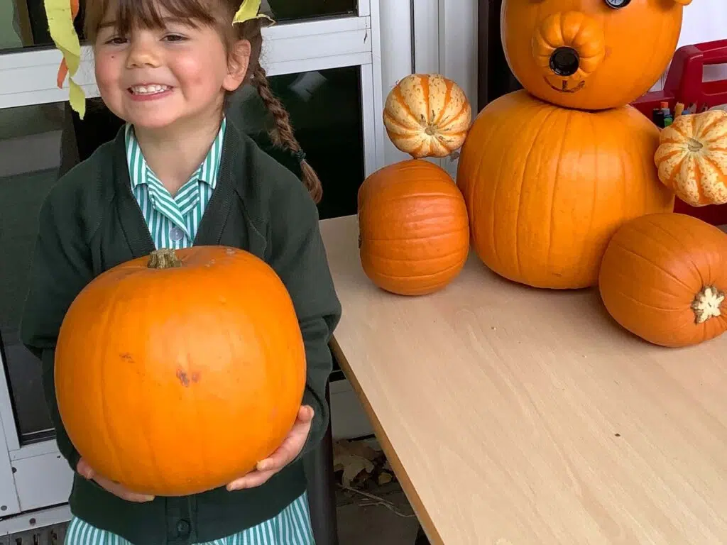 Early Years pupil with a pumpkin
